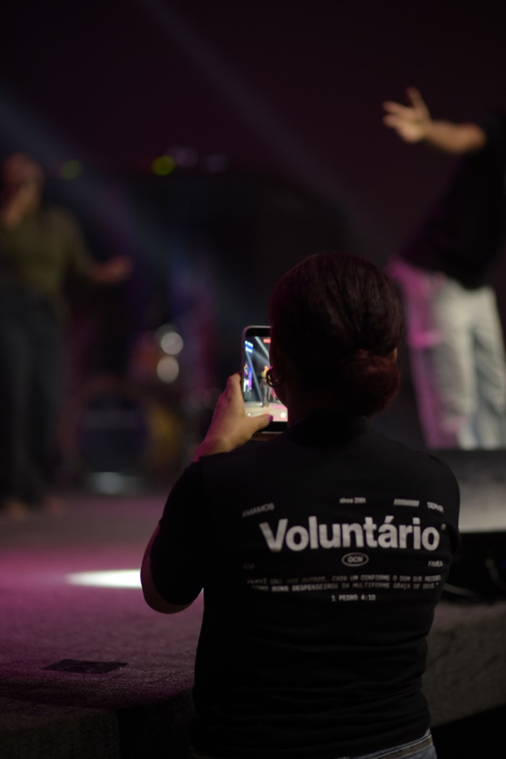 Voluntária da equipe de mídia gravando o culto com o iPhone